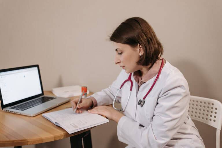 Medical professional reviewing patient records for telehealth consultation.