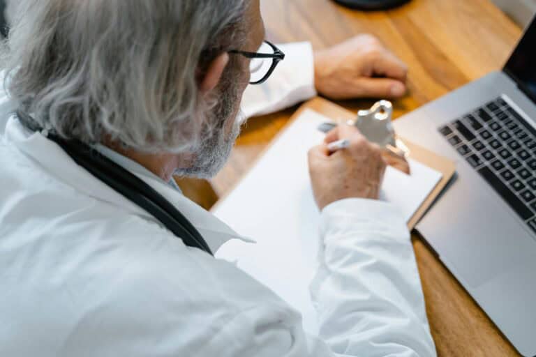 Healthcare professional conducting telehealth consultation via laptop.