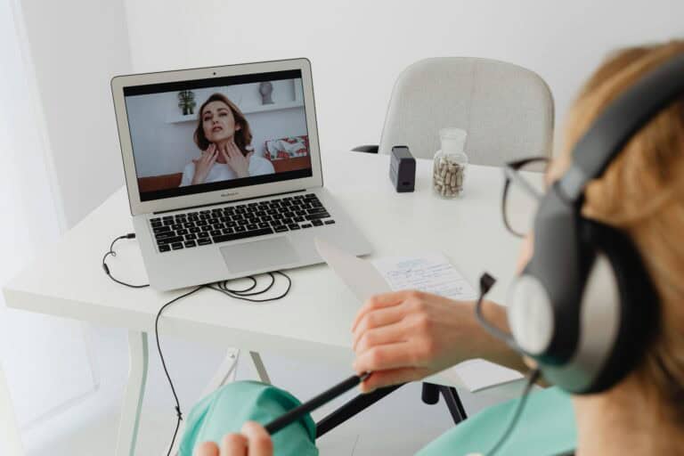 Telehealth doctor consultation with a female patient via laptop and headset.