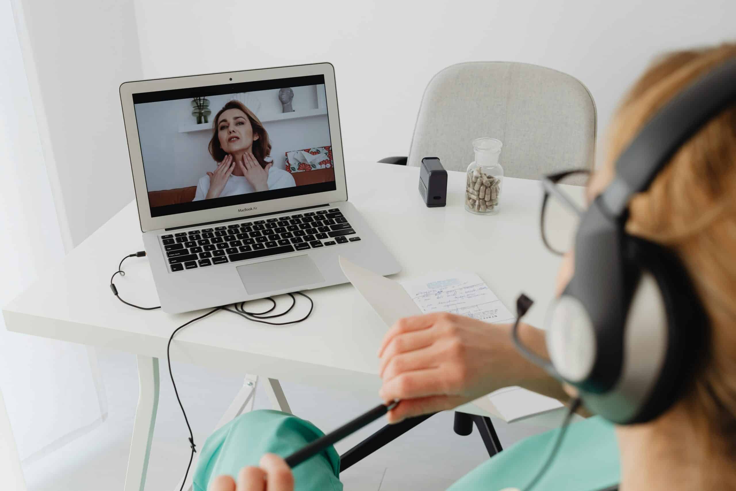 Telehealth doctor consultation with a female patient via laptop and headset.