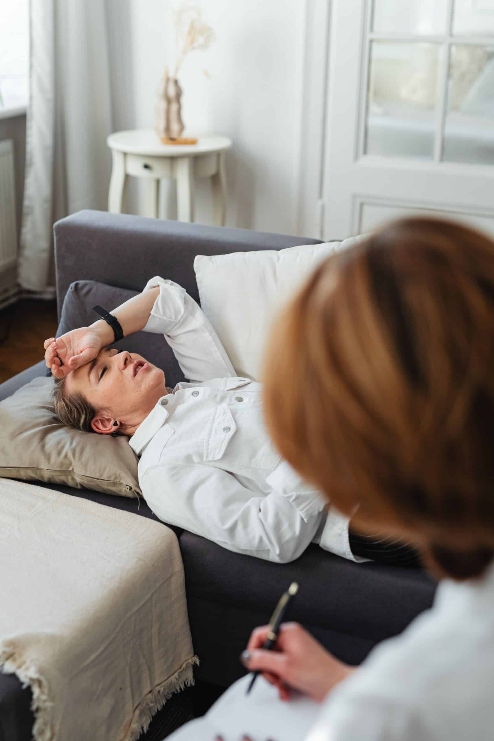 Woman lying on sofa during telehealth medical consultation at home.
